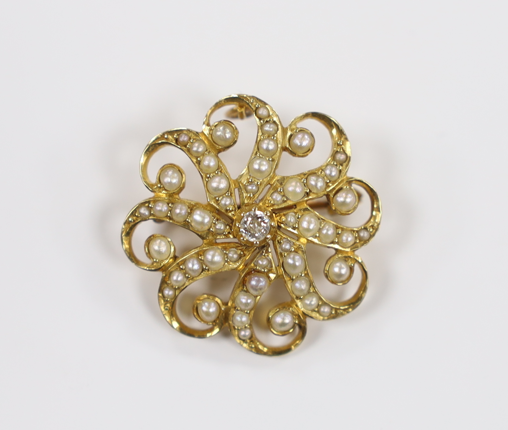 An Edwardian 15ct, seed pearl cluster and single stone diamond set circular brooch, 23mm, gross weight 4.8 grams.